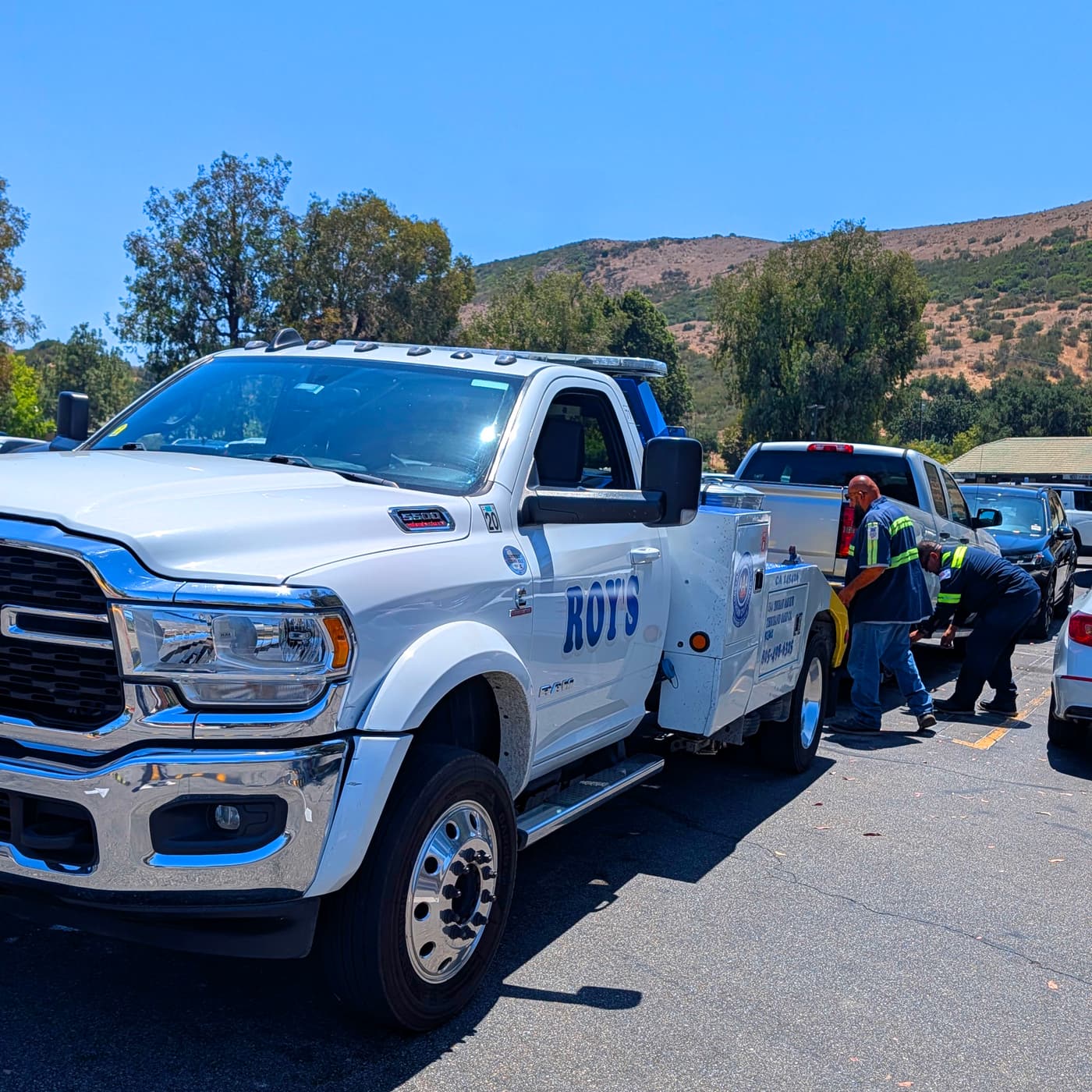 A tow truck crew hooking up a vehicle in a commercial parking lot